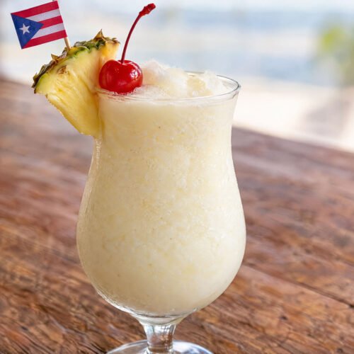 Creamy Puerto Rican Piña Colada with pineapple and coconut in a white cocktail glass