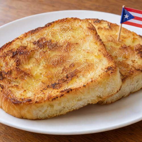 Golden Puerto Rican tostadas de pan sobao with butter, crisp edges, and soft centers on a white plate