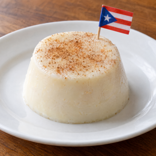 Individual Puerto Rican tembleque de coco topped with cinnamon on a plain white plate